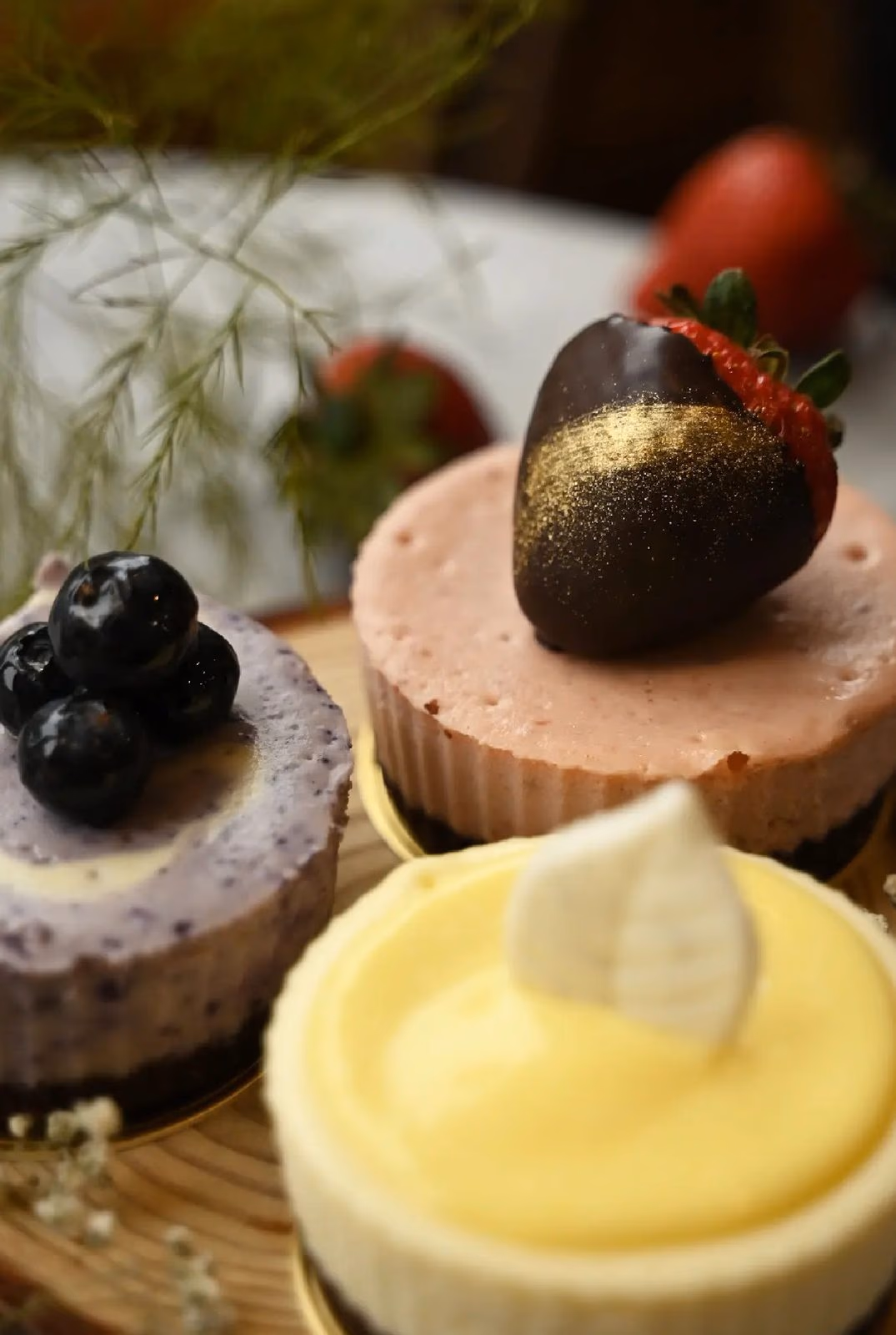 Blueberry, strawberry and lemon cheesecakes side by side