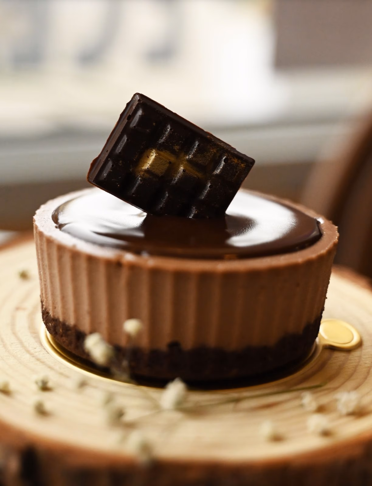 A chocolate cheesecake topped with a square of dark chocolate